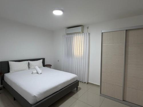 une chambre avec un lit blanc et une fenêtre dans l'établissement Mila apartment, à Eilat