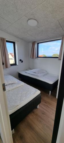 two beds in a room with two windows at Sandkaas Family Camping & Cottages in Allinge