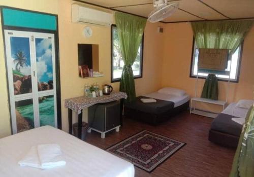 a bedroom with two beds and a table in a room at Mersing Barokahhill Beach Resort in Kampong Tanjong Resang