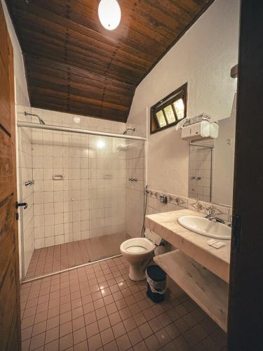 a bathroom with a shower and a toilet and a sink at Hotel Pousada Cata Branca in Itabirito