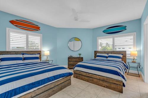 Dos camas en una habitación con paredes y ventanas azules. en Serene Home with Skiff Dockage & Access to Private Bayfront Beach, en Lower Matecumbe Beach