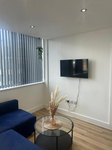 a living room with a blue couch and a glass table at Elegant 1 Bed Flat Near Stadium & Shops and free parking in Manchester