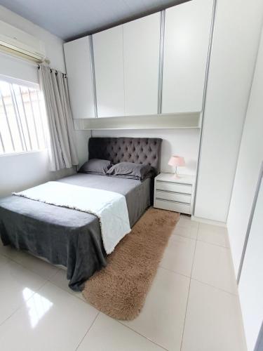 a bedroom with a bed with white cabinets and a rug at Casa Completa em Foz do Iguaçu in Foz do Iguaçu