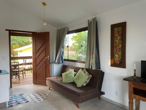 un soggiorno con divano marrone e finestra di Hospedaria Canto Itaúnas a Itaúnas