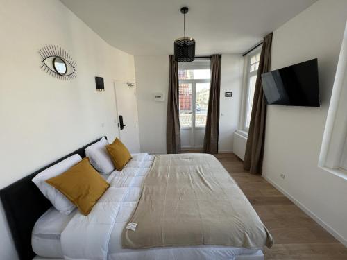 a bedroom with a large white bed with yellow pillows at La Suite Balneo 2p - centre ville in Liévin