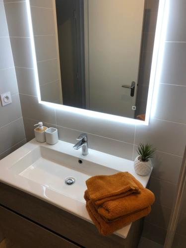 Un lavabo de baño con un espejo y una toalla. en STUDIO 38 m2 Point Zéro, en La Grande-Motte