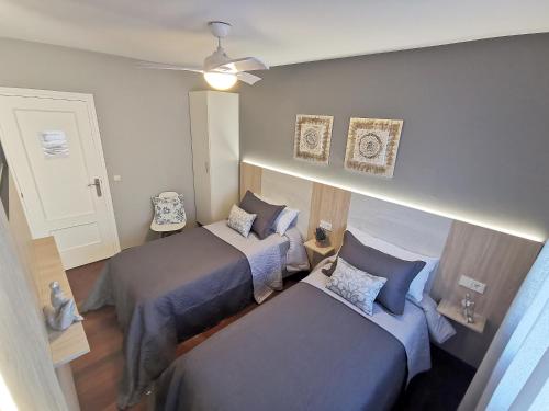 a bedroom with two beds and a ceiling fan at Pensión Atenea & Via Romana - Grupo Arcanos in Caldas de Reis
