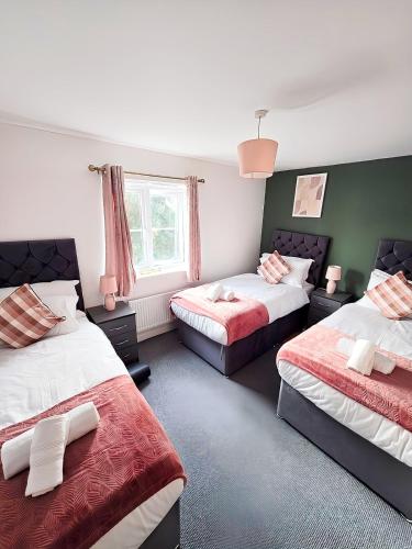 a bedroom with two beds and a window at Spacious 3-Bed Townhouse in Bilston, Sleeps 9, Driveway Parking, Near M6 & Wolverhampton in Bilston