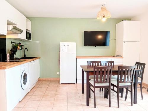 a kitchen with a table and chairs and a refrigerator at T3 Famille - piscine, aire de jeux - Barbaste in Barbaste