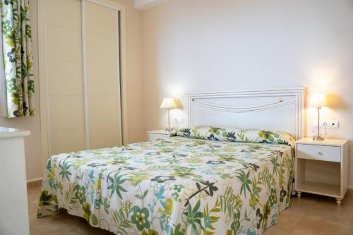 a bedroom with a bed with a floral bedspread at Apartamentos Esmeralda Suites Unitursa in Calpe