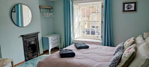 a bedroom with a bed and a mirror and a window at Bluebird Cottage in Pickering