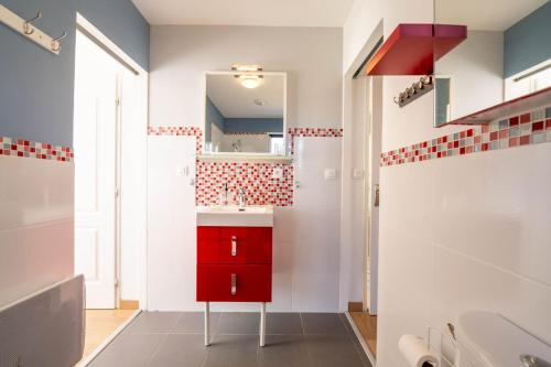 a bathroom with a red cabinet and a red mirror at La Villa Océane, familiale & piscine privée in Guidel