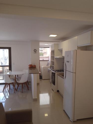 a kitchen with a white refrigerator and a table at Praia Mansa Caioba in Matinhos