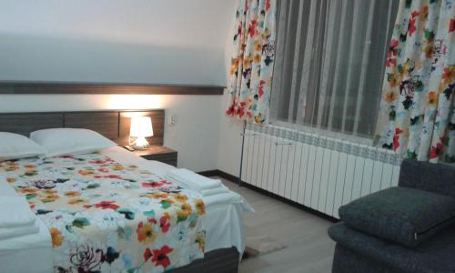 a bedroom with a bed and a chair and a window at Къща за гости Семейство Петрови in Kalofer