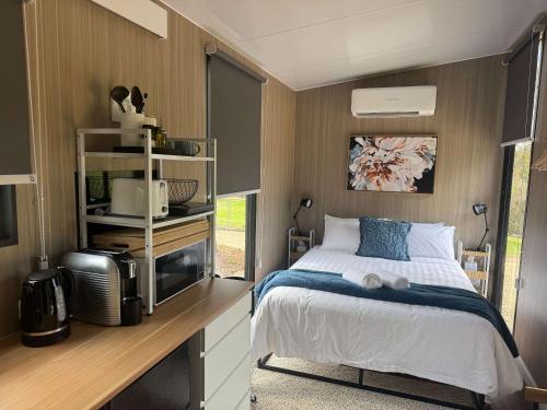 a bedroom with a bed and a desk with a microwave at Gruyere Falls by Tiny Away in Gruyere