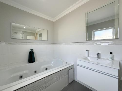 Un baño blanco con bañera y lavabo. en Vida Tranquilo, en Edgemead