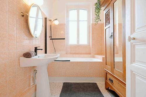 een badkamer met een wastafel en een ligbad bij Villa des Genêts in Saint-Pair-sur-Mer