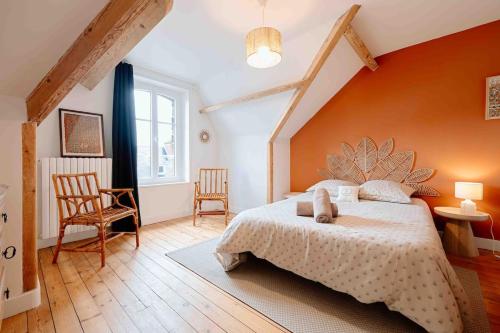 een slaapkamer met een groot bed met een oranje muur bij Villa des Genêts in Saint-Pair-sur-Mer
