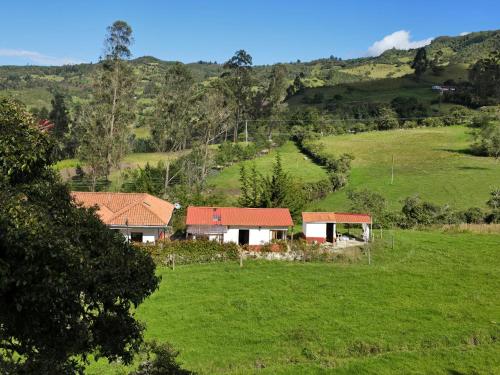 a house in the middle of a green field at Finca santa helena in Machetá