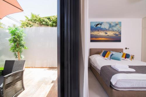 a bedroom with a bed and a balcony with a window at HaBaitBe Matityahu By Domus in Beer Sheva