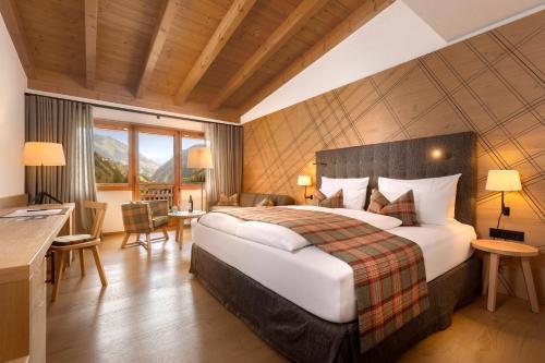 um quarto de hotel com uma cama grande e uma escrivaninha em Defereggental Hotel & Resort em Sankt Veit in Defereggen