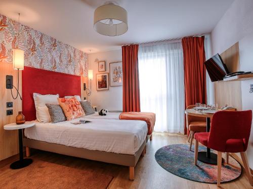 a hotel room with a bed and a table and a desk at Séjours & Affaires Angers Atrium in Angers