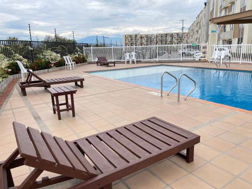 a swimming pool with two benches and a picnic table at Loft Moderno con aire , con piscina T12 in Neiva