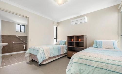 a bedroom with two beds and a bathroom with a sink at Beach Shack 6 in Preston Beach