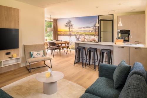 a living room with a couch and a kitchen at Dormio Resort De Hondsrug in Gasselte