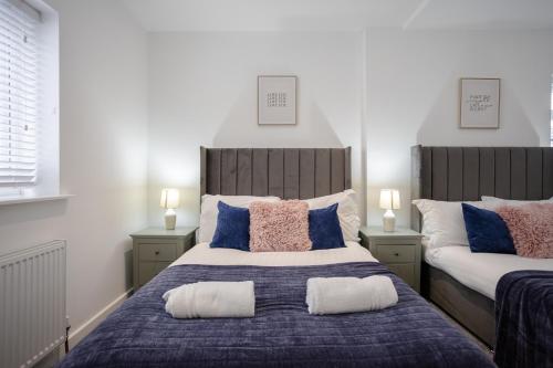 1 Schlafzimmer mit 2 Betten mit blauen und rosa Kissen in der Unterkunft Bespoke Apartments Near Cardiff City Centre Free Parking in Cardiff