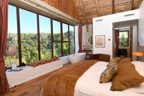 a bedroom with a large bed and large windows at La Grange de Magdeleine in Salles-la-Source