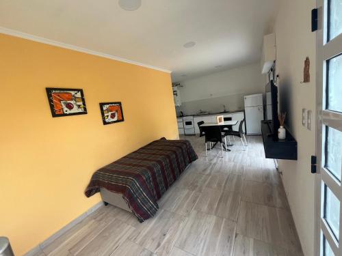 Un dormitorio con paredes amarillas y una cama y una mesa. en Cabañas del monte, en Monte Hermoso