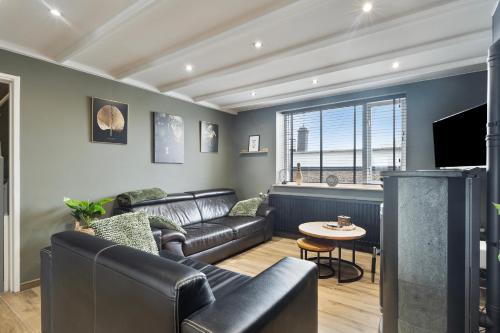 a living room with a couch and a tv at Graafjansdijk B Vakantiehuis met 3 slaapkamers net over de Belgische grens in Westdorpe