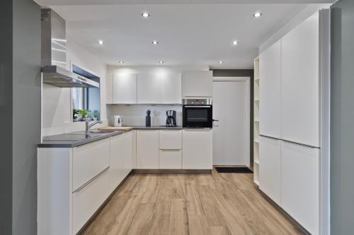 a kitchen with white cabinets and a wooden floor at Graafjansdijk B Vakantiehuis met 3 slaapkamers net over de Belgische grens in Westdorpe