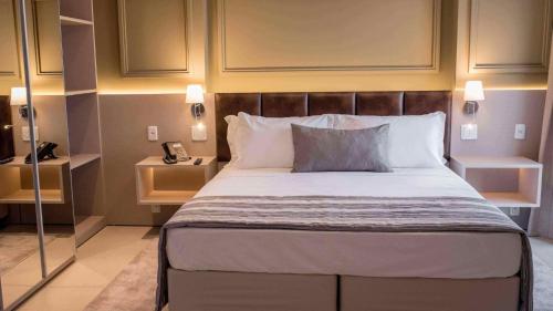a bedroom with a bed and a phone in it at Hplus Premium Palmas in Palmas