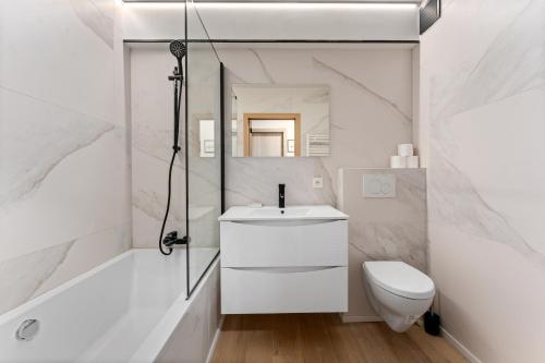 a white bathroom with a sink and a toilet at Sparrenduin - Compact en cosy app aan golf De Haan in De Haan