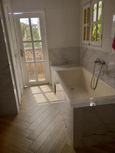 a white bathroom with a tub and a window at MAISON Khadija Abibatou in Dakar