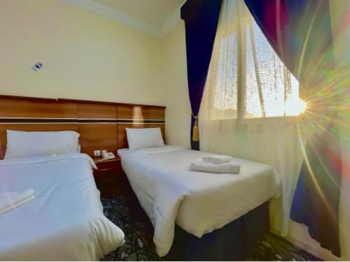 a hotel room with two beds and a window at فندق تارا المحبس - محبس الجن - in Makkah