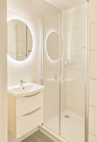 a white bathroom with a shower and a sink at CityNest Hannover O5 in Hannover