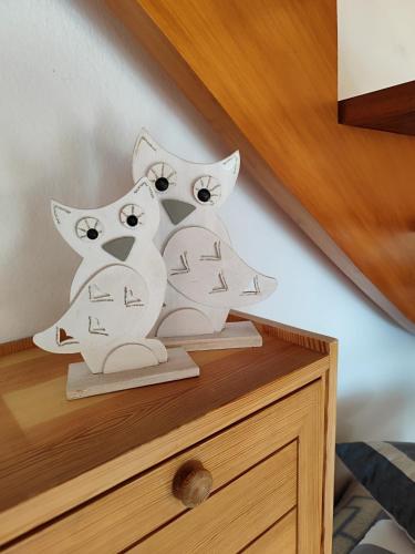 Ferienhaus Eulenburg am Reuthsee في Sulzdorf an der Lederhecke: تمثالان لقطتين بيضاوين على طاولة بجانب السرير