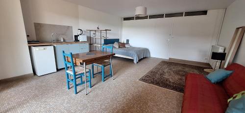 a kitchen with a table and blue chairs in a room at studio indépendant dans maison à la campagne in Lagor