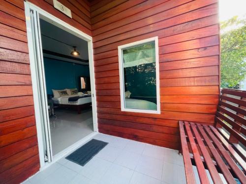 a red house with a bench and a window at the noi family house in Ko Lipe