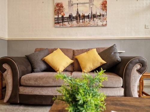 a brown couch with yellow pillows in a living room at Devon St - Cozy home, Free easy parking! in Hull