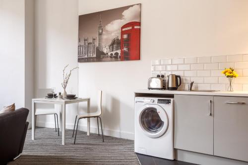 a kitchen with a washing machine and a table at Modern City Centre Apartment in Bradford in Bradford