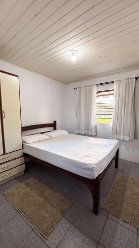 a large white bed in a room with a window at Chalés Paraíso das Ilhas - Alto Cedros. in Rio dos Cedros