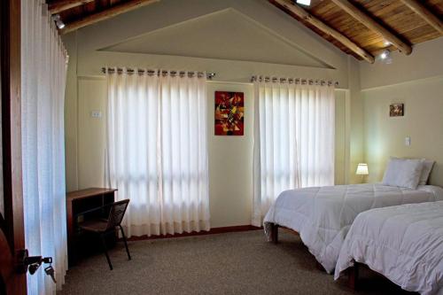 Un dormitorio con una cama y una ventana con cortinas. en Veronica lookout Hotel, en Urubamba