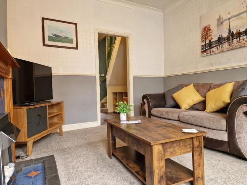 a living room with a couch and a tv at Devon St - Cozy home, Free easy parking! in Hull