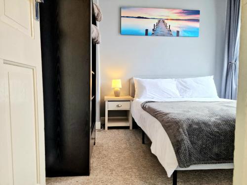 a bedroom with a bed and a night stand with a lamp at Devon St - Cozy home, Free easy parking! in Hull