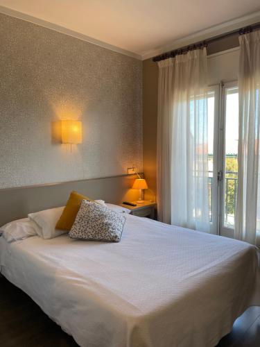 a bedroom with a large white bed with a window at Hotel Esteba in Caldes de Malavella