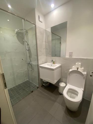a bathroom with a toilet and a shower and a sink at The Lennox at Airport City, Accra in Accra